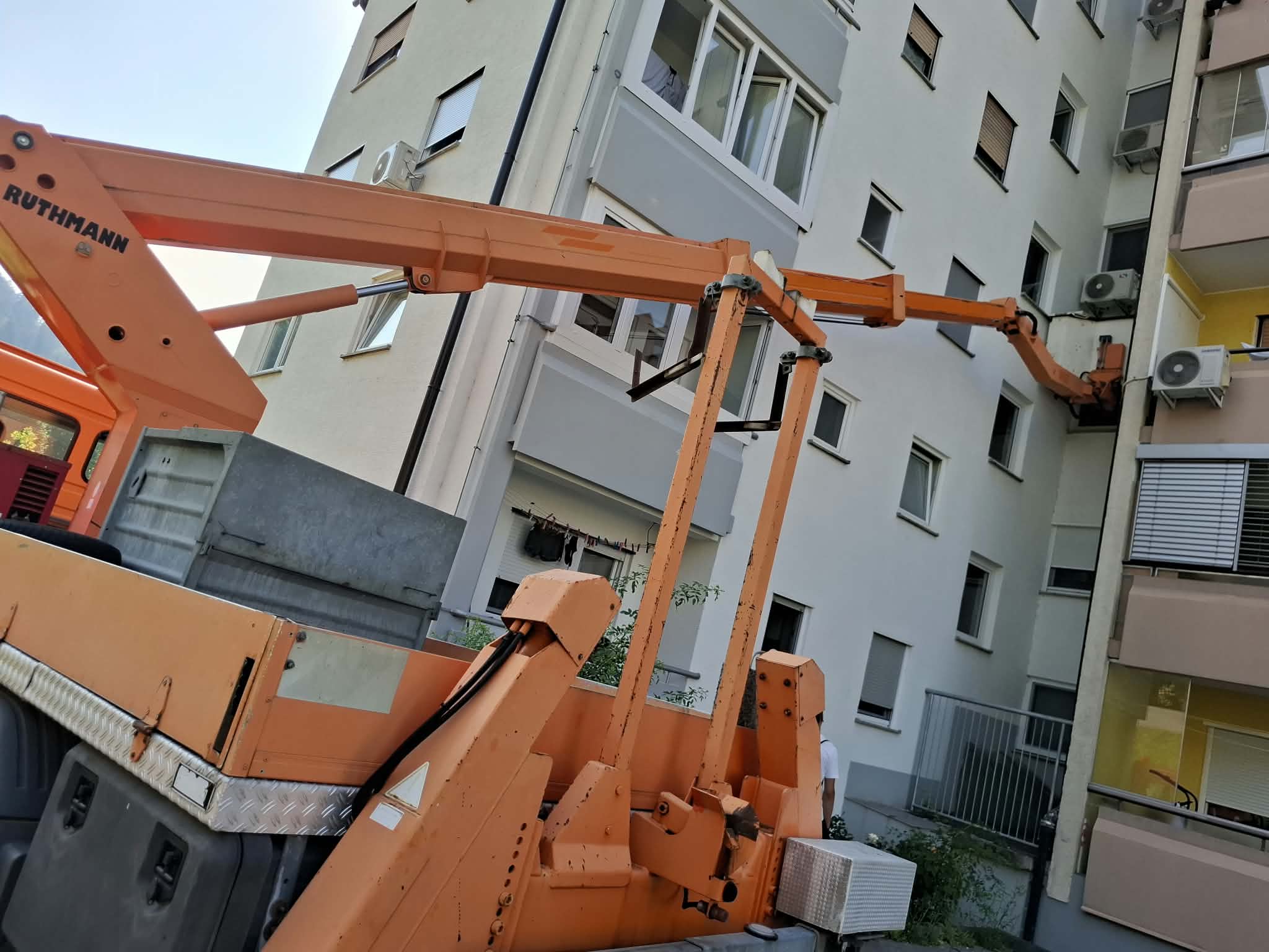 Avtodvigalo s košaro med delom ob večstanovanjski stavbi